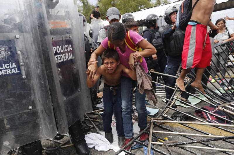 Central American migrants break through a police barricade, on the Mexico-Guatemala border.
