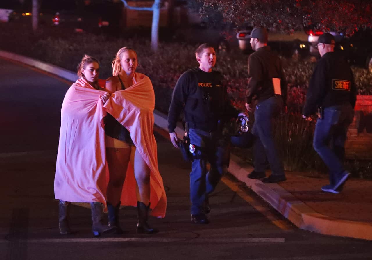 Two women wearing blankets leave the area near the Borderline Bar and Grill in Thousand Oaks, California