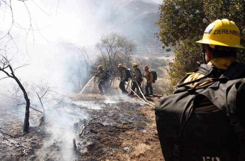 Firefighters work to extinguish a flare-up of the Woolsey Fire on a hillside in West Hills, California, USA, 11 November 2018.