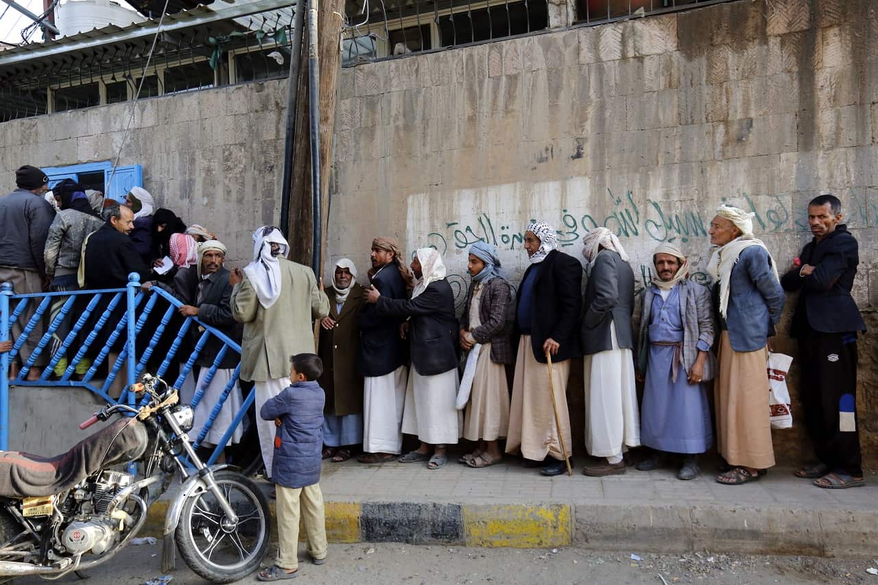 Yemenis line up to receive food from a charity.