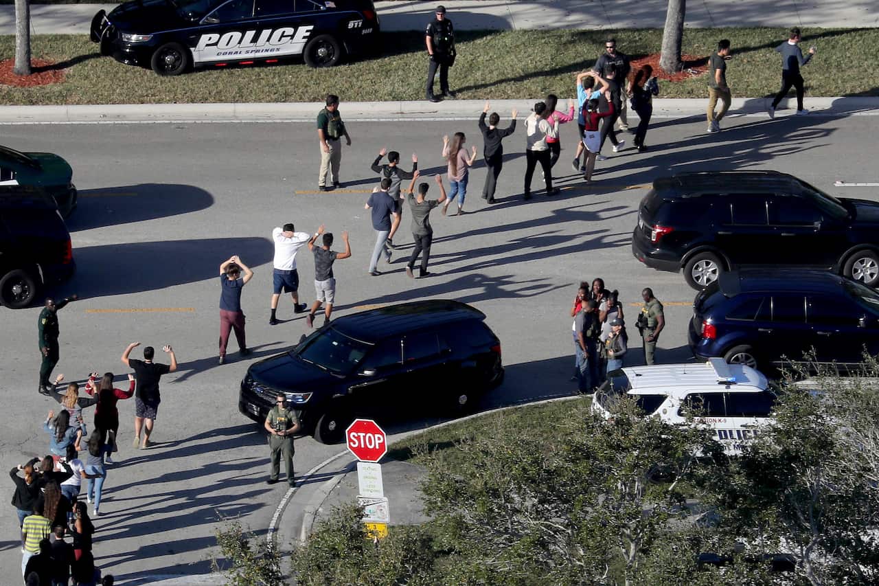 Students hold their hands in the air as they are evacuated by police from Marjory Stoneman Douglas High School in Parkland, Fla., on Feb. 14, 2018, after a shooter opened fire on the campus.