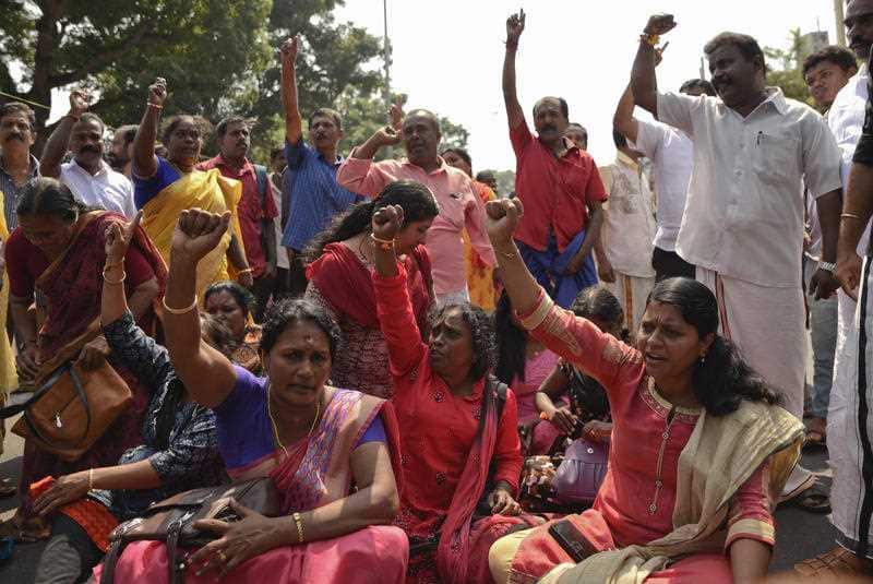 Protestors block traffic and shout slogans after two women entered the Sabarimala temple.