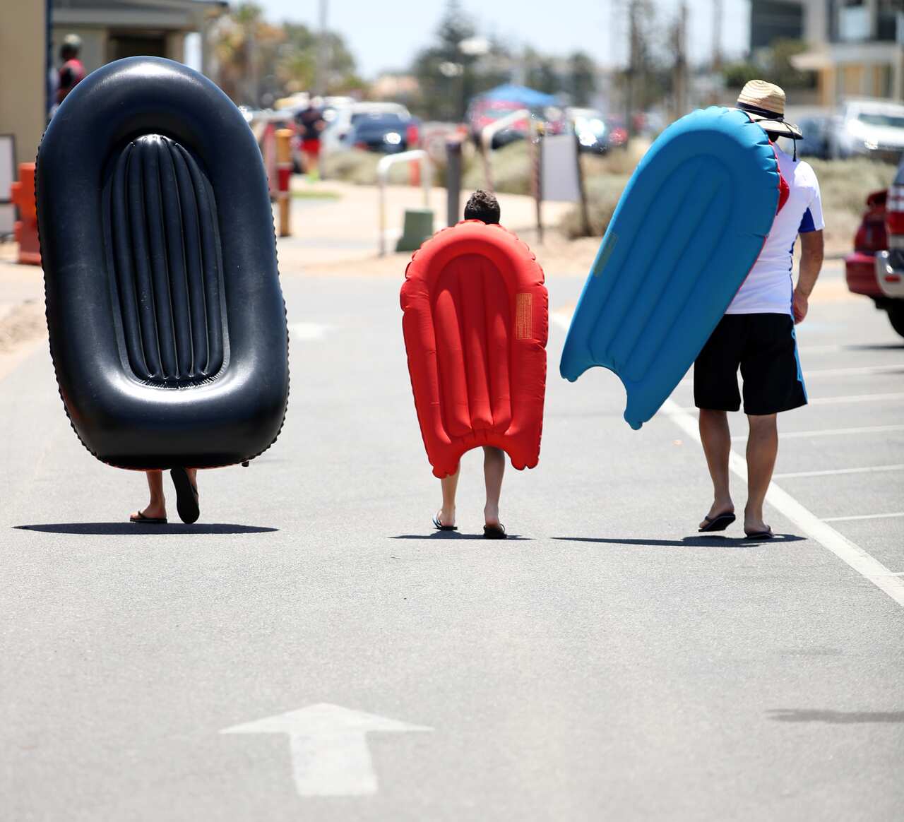 Beach goers cart their inflatable boats to West Beach during a hot day in Adelaide.