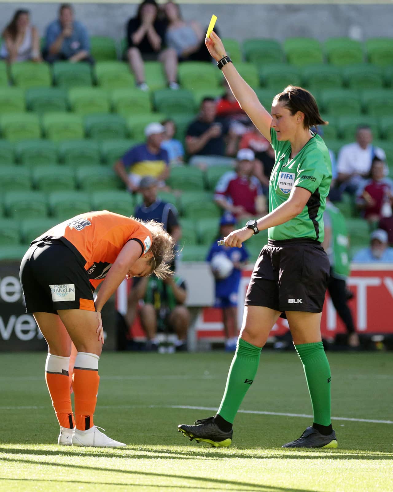 Referee Kate Jacewicz gives a yellow card to Jenna McCormick of the Brisbane Roar.