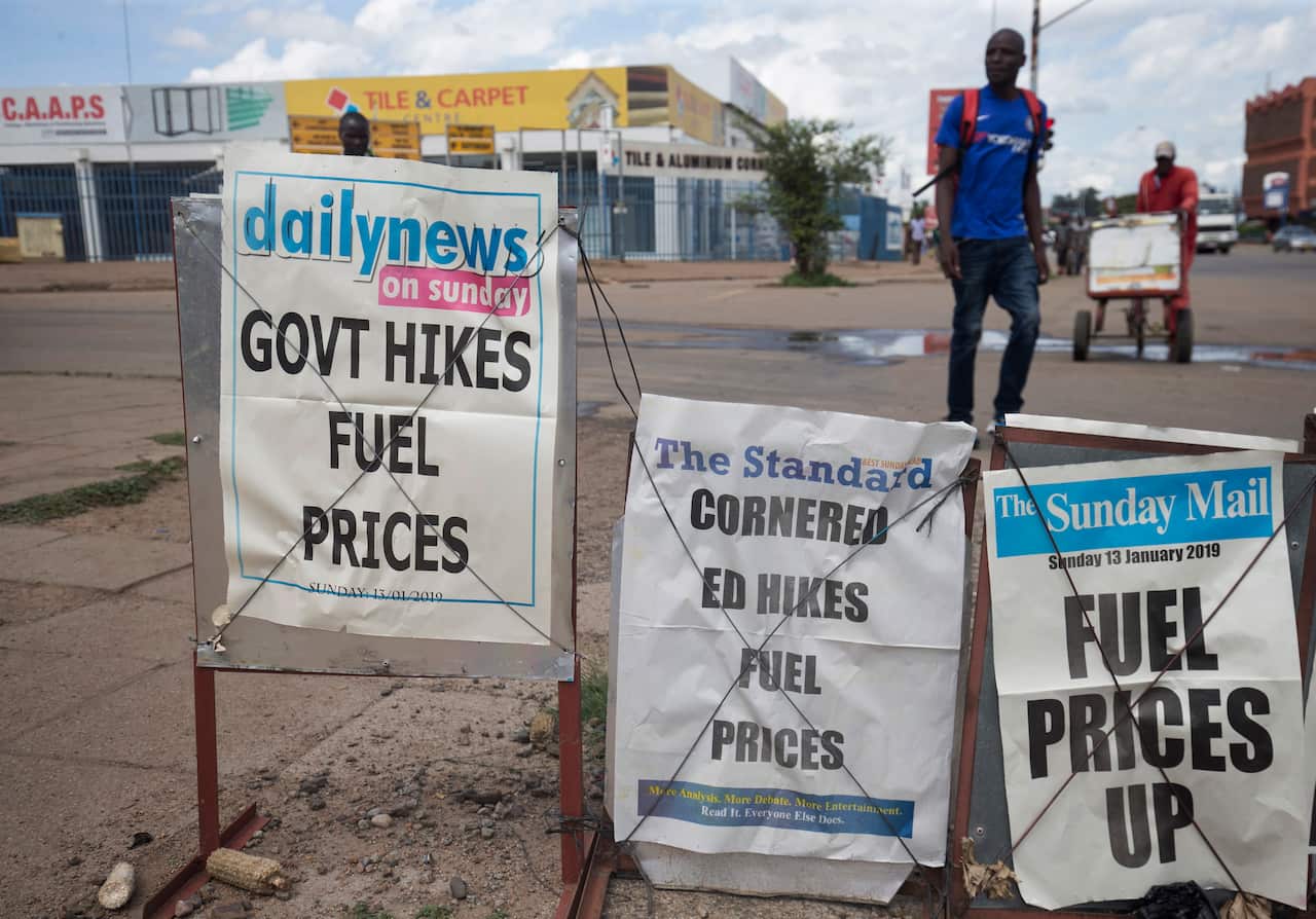 Members of the public walk past newspaper placards heading up the fuel price increase, in Harare, Zimbabwe.
