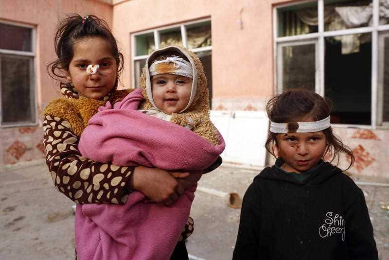 Afghan girls, who were injured in a bomb blast a day earlier, pose for a photograph at the scene of the blast.