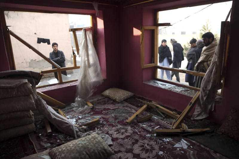 Afghan villagers stand near a house destroyed by the blast.