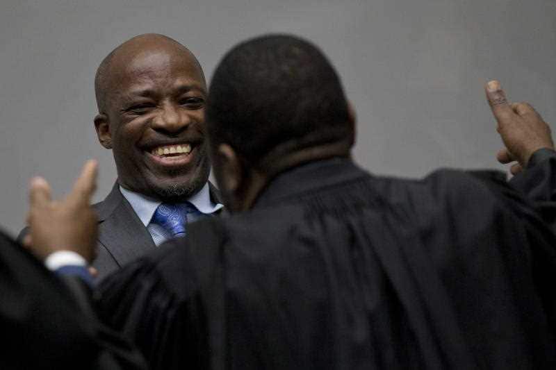 Charles Ble Goude hugs his legal team as he enters the courtroom of the International Criminal Court.