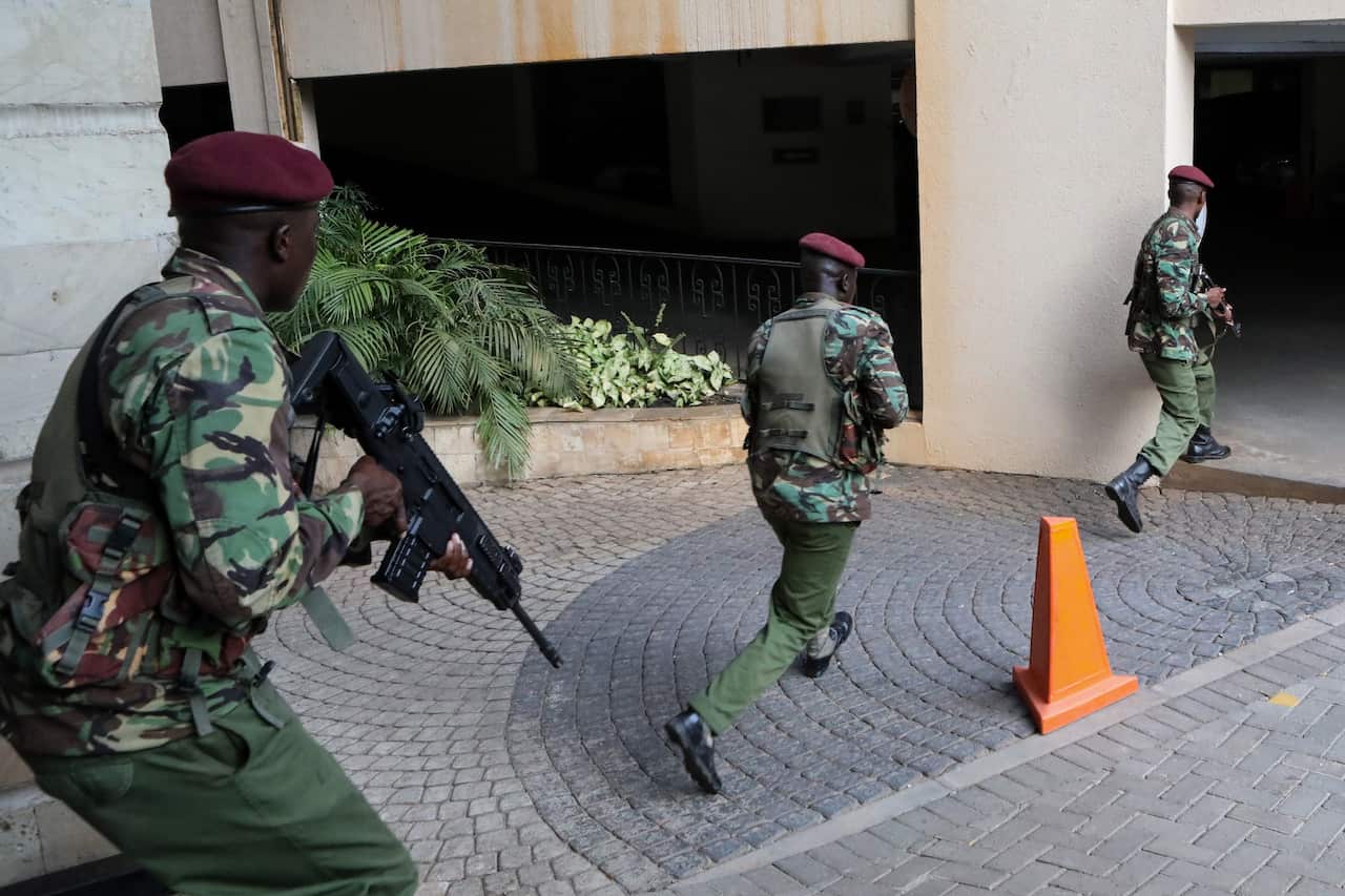 Kenyan police officers take cover during an ongoing gunfire and explosions.