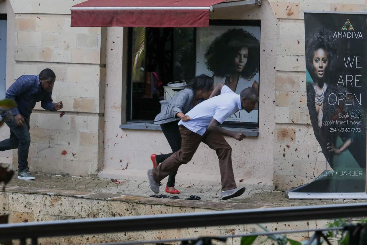 Men and a woman take cover as they escape to safety.