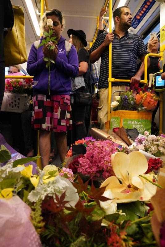 People ride the 86 tram with flowers for Aiia Maasarwe