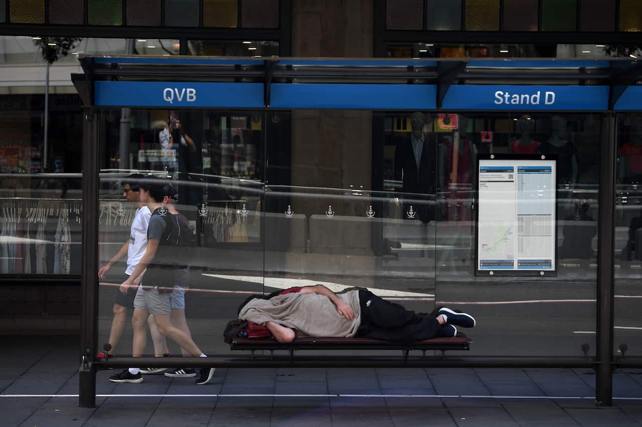 A man is seen sleeping in a bus shelter outside the Queen Victoria Building in Sydney, Wednesday, January 23, 2019. (AAP Image/Dan Himbrechts) NO ARCHIVING