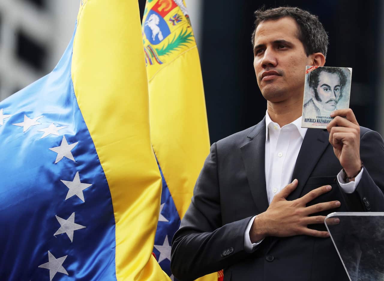 Juan Guaido, President of the Venezuelan Parliament, poses with a copy of Venezuela's consitution as he announces that he assumes executive powers.