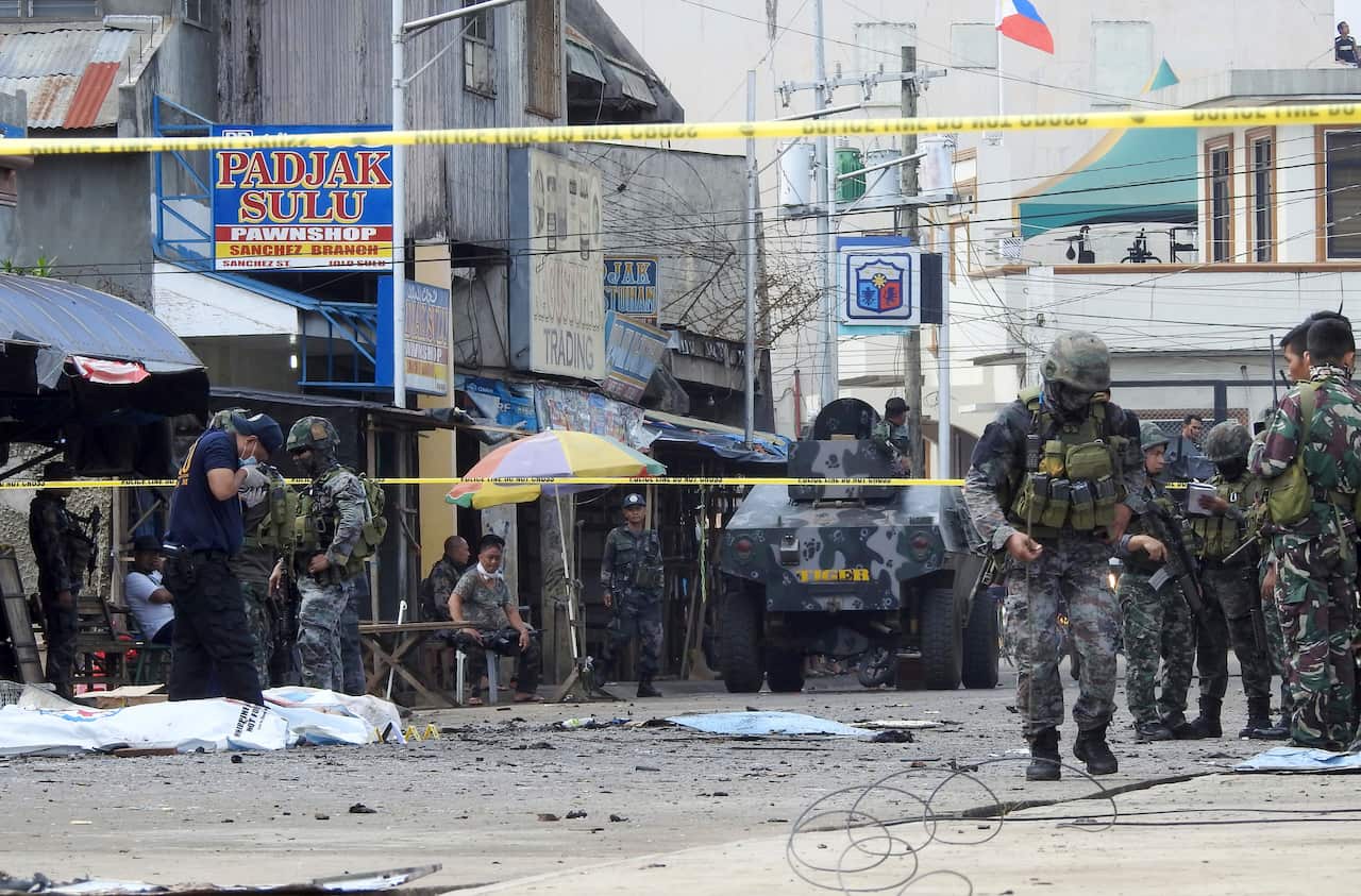 Police investigators and soldiers attend the scene after two bombs exploded outside a Roman Catholic cathedral in Jolo.