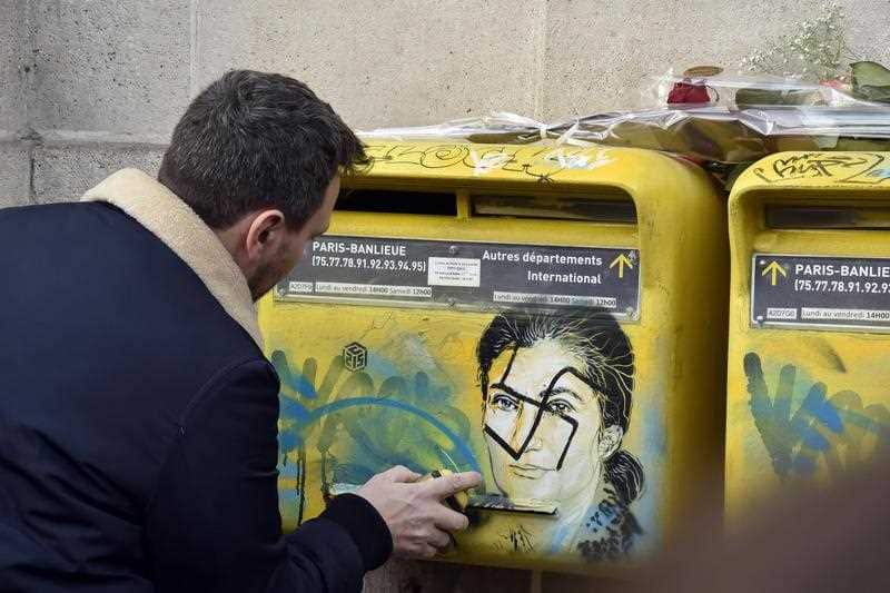 A man cleans the mailboxes with the effigy of Simone Weil after a swastika was tagged in Paris, France.