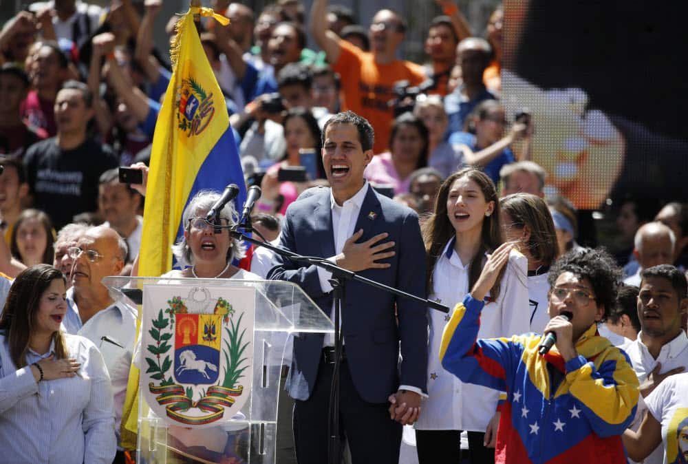 Venezuela' self-proclaimed interim president Juan Guaido sings the national anthem as thousands march against President Nicolas Maduro.