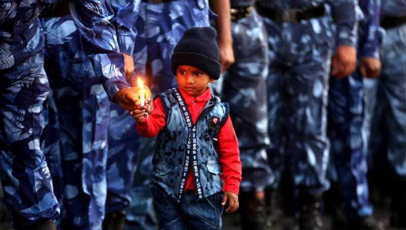 Rapid Action Force (RAF) soldiers and a child from one of their families hold candles as they pay tibute to the killed Indian Central Reserve Police Force.