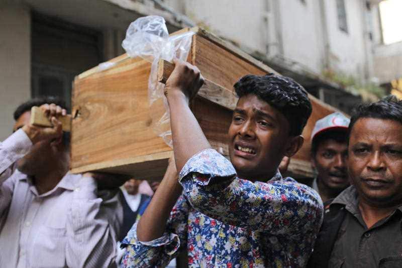 A Bangladeshi boy cries as he carries the coffin of a relative who died in the fire.