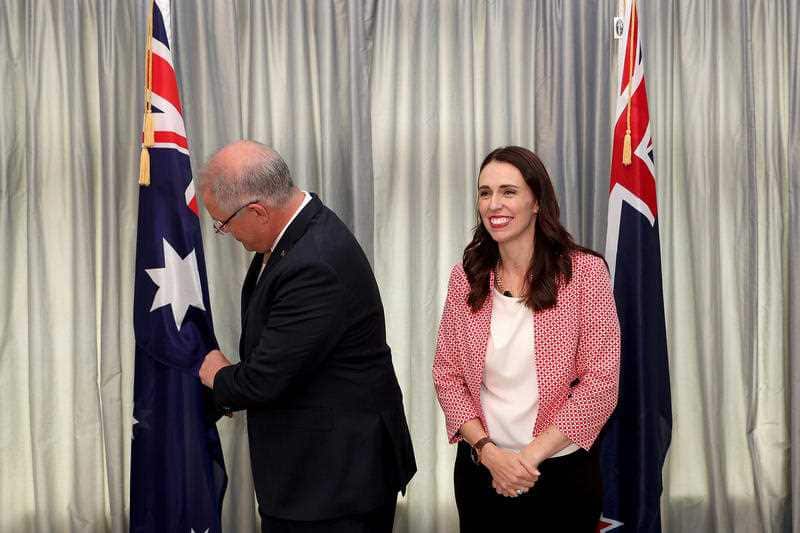 Australian Prime Minister Scott Morrison checks the an Australian flag during a meeting with New Zealand Prime Minister Jacinda Ardern