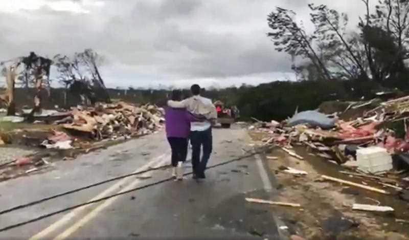 People walk amid debris in Lee County.