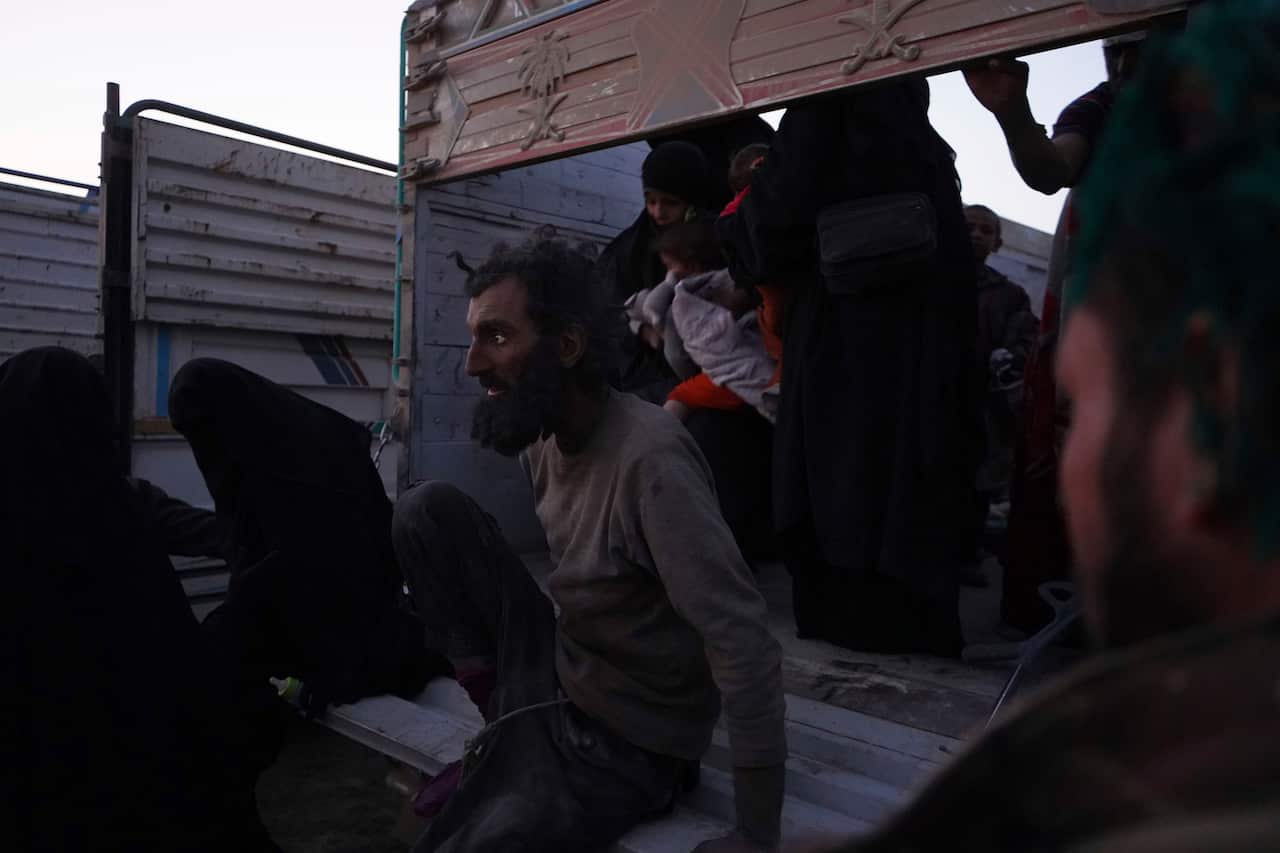 People climb off of a truck after being evacuated out of the last territory held by Islamic State militants, outside Baghouz, Syria.