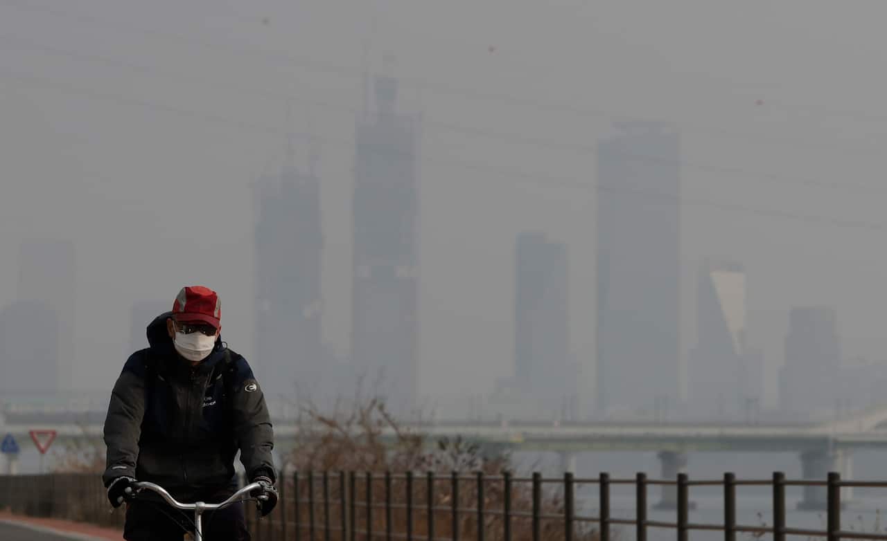 A man wearing a mask rides a bicycle along the Han river in Seoul, South Korea.