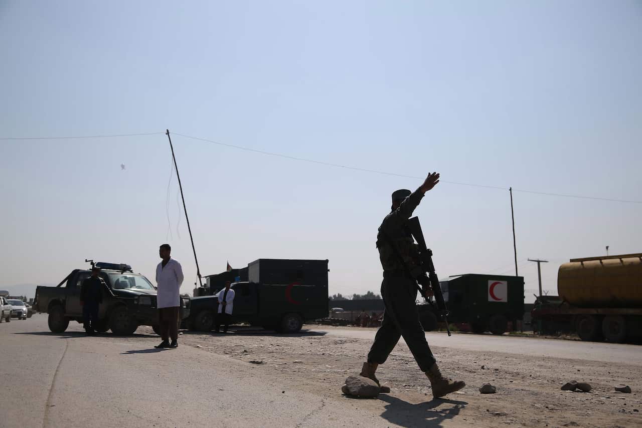 Afghan security officials secure the road leading to the scene of a suicide bomb attack near the airport in Jalalabad, Afghanistan.