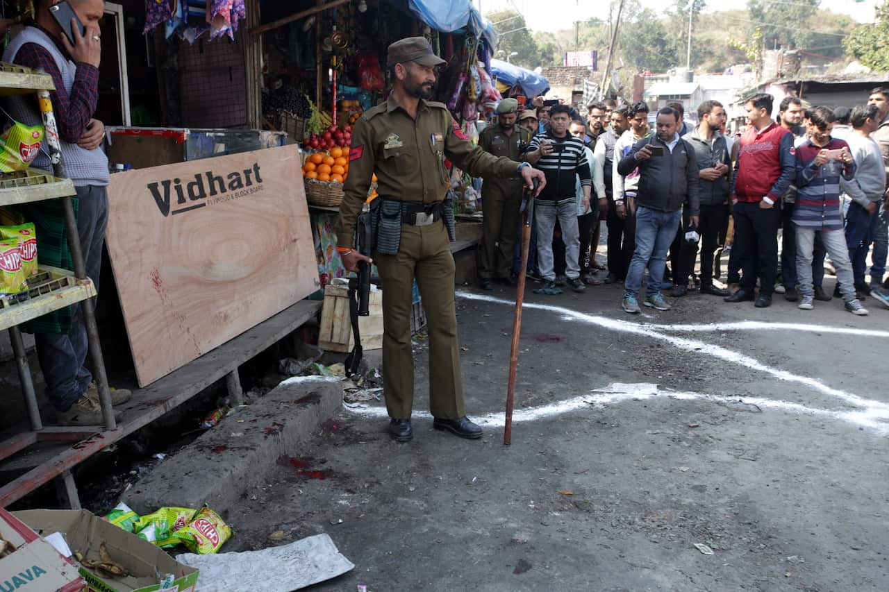 Indian paramilitary soldiers stand guard near a grenade blast site, at a general bus stand in Jammu, the winter capital of Kashmir, India.