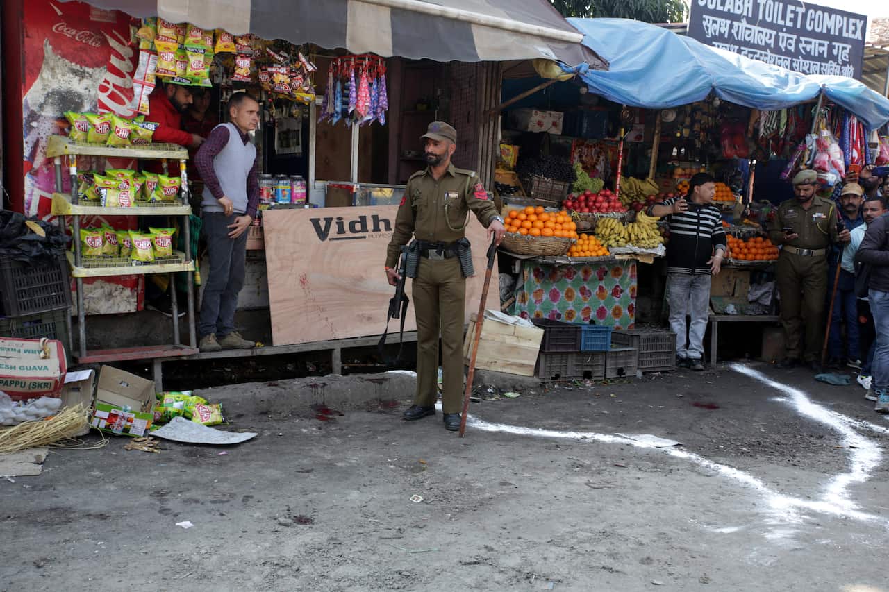 Indian paramilitary soldiers stand guard near a grenade blast site, at a general bus stand in Jammu, the winter capital of Kashmir, India.