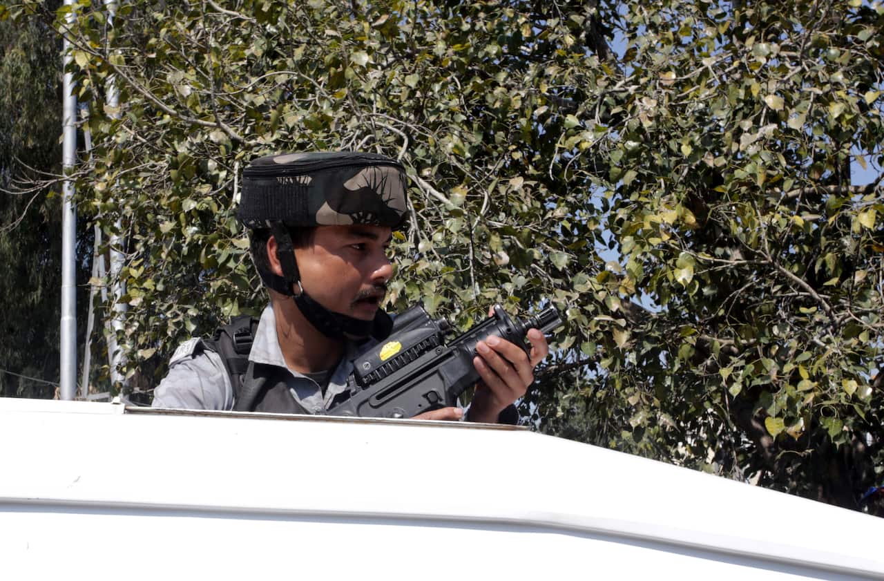 An Indian paramilitary soldier stands guard near a grenade blast site, at a general bus stand in Jammu, the winter capital of Kashmir, India.