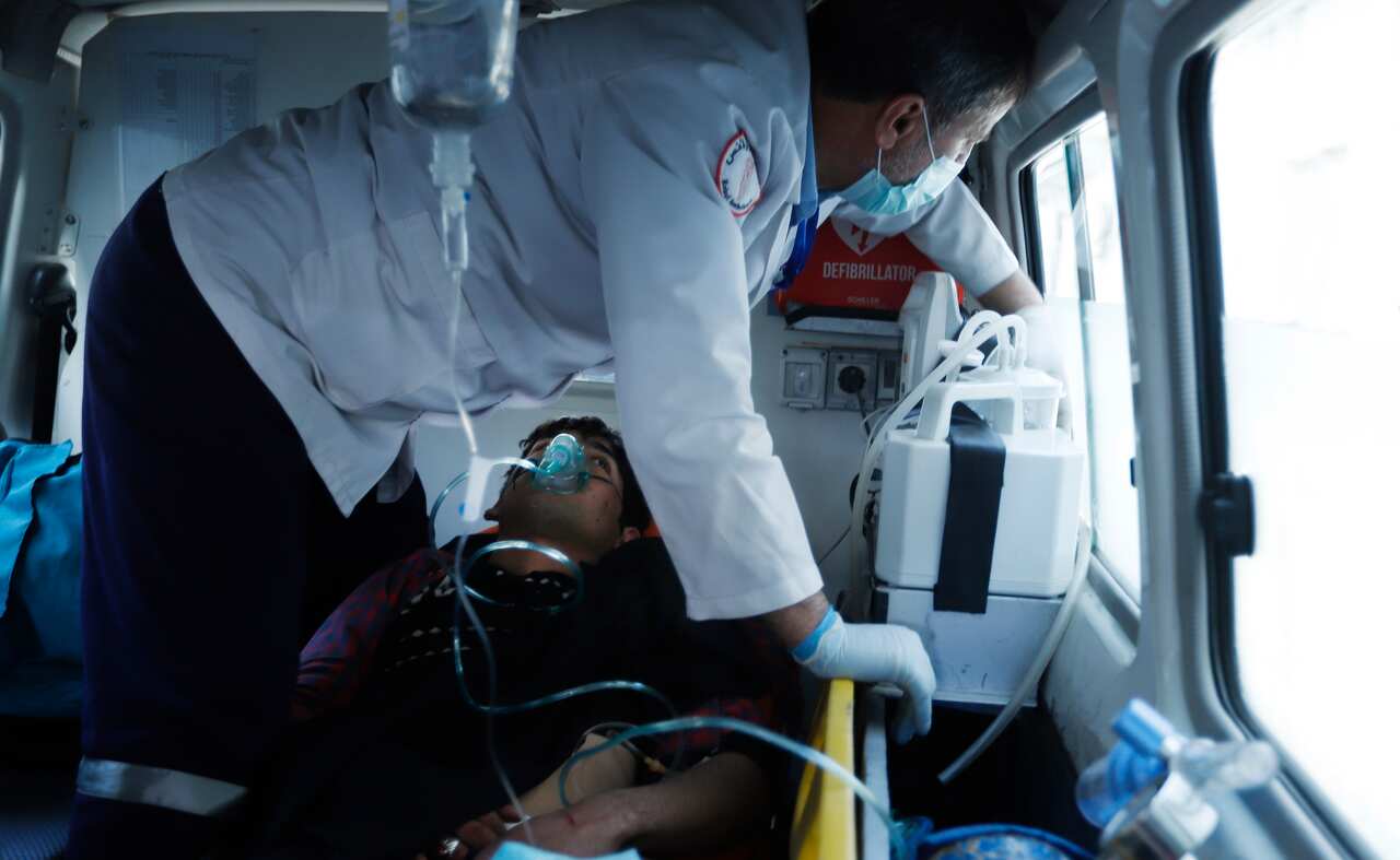 Afghan health workers carry a wounded person to a hospital after several mortars targeted a political gathering in downtown Kabul, Afghanistan.