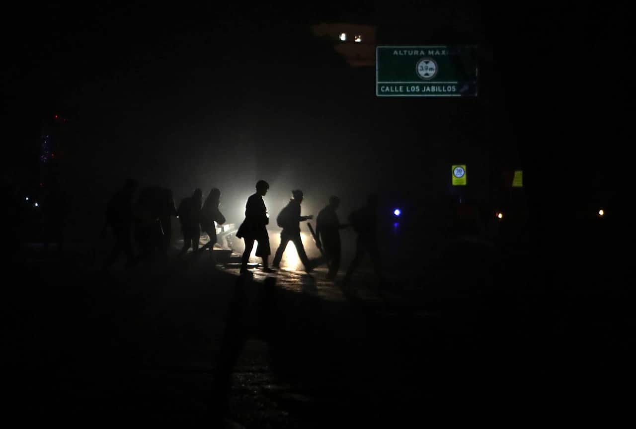 People walk in a street in the dark during a power outage in Caracas, Venezuela.