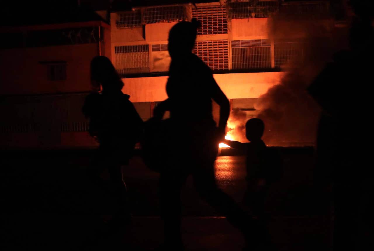 People walk in a street in the dark during a power outage in Caracas, Venezuela.