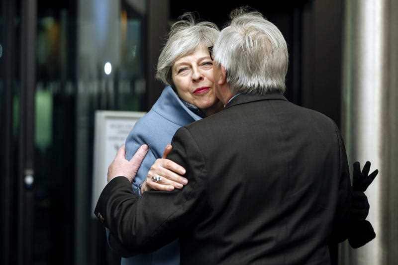 British Prime Minister Theresa May, background, is welcomed by European Commission President Jean-Claude Juncker