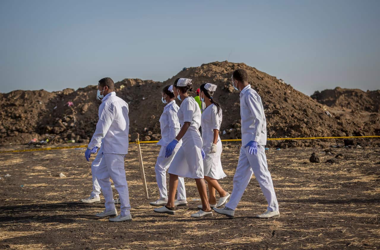 Nurses walk to collect materials at the scene where the Ethiopian Airlines Boeing 737 Max 8 crashed shortly after takeoff in Ethiopia.
