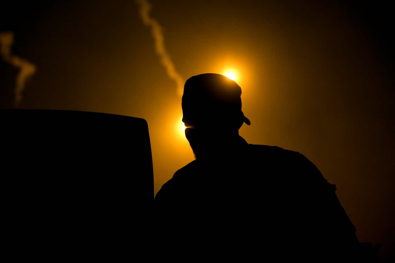 A U.S.-backed Syrian Democratic Forces (SDF) fighter watches illumination rounds light up Baghouz, Syria.