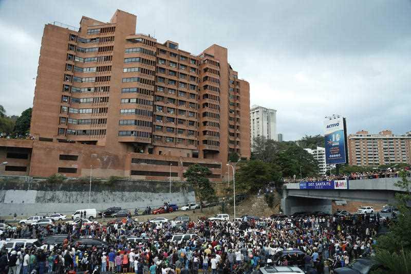 Standing on a vehicle rooftop, front, National Assembly President Juan Guaido speaks to supporters as he visits different anti-government protests in Caracas, Venezuela