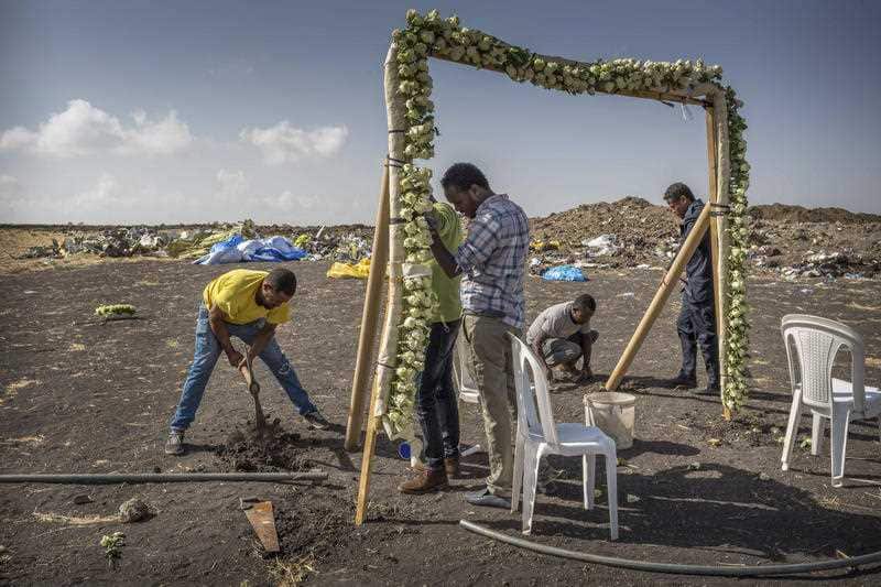 Workers erect floral installations at the scene