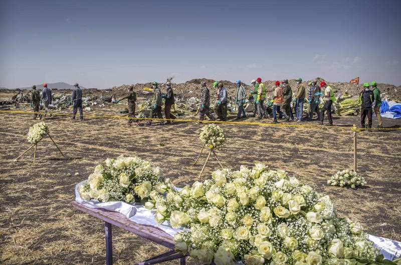 Workers walk past flowers laid at the scene