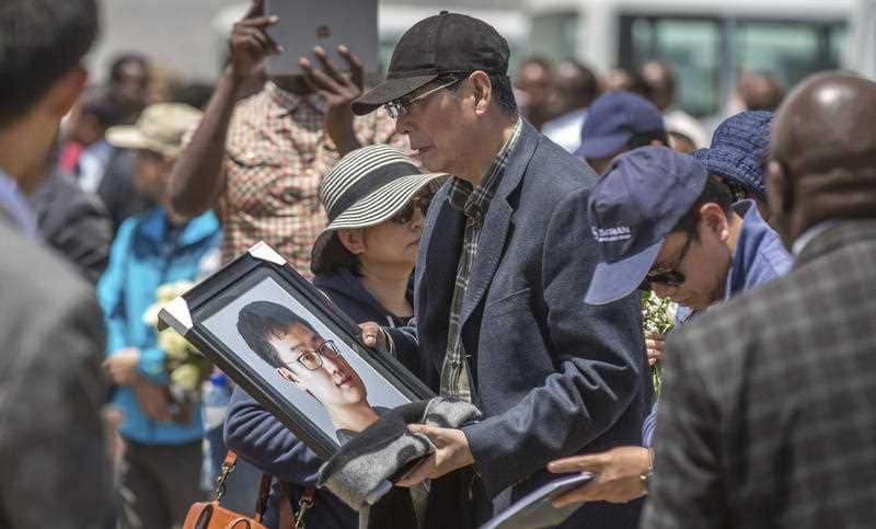 A family member holds a framed photo of loved one at the scene
