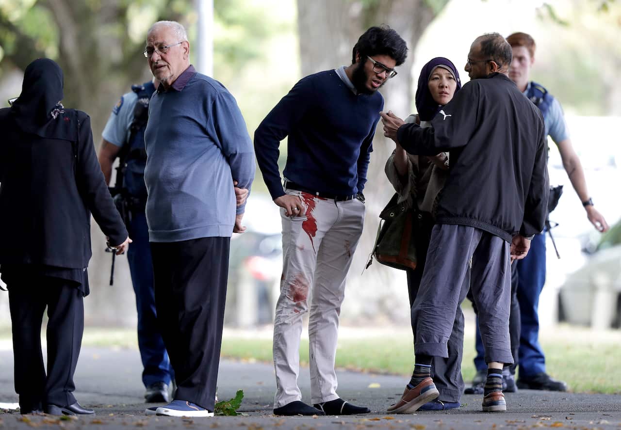 People stand across the road from a mosque in central Christchurch, New Zealand, Friday.