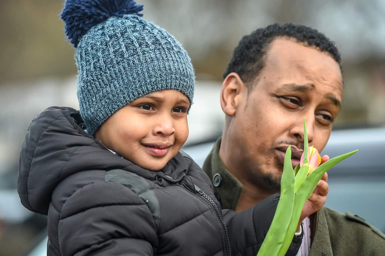 Said Abdi's son holds a flower given to him outside Birmingham Central Mosque