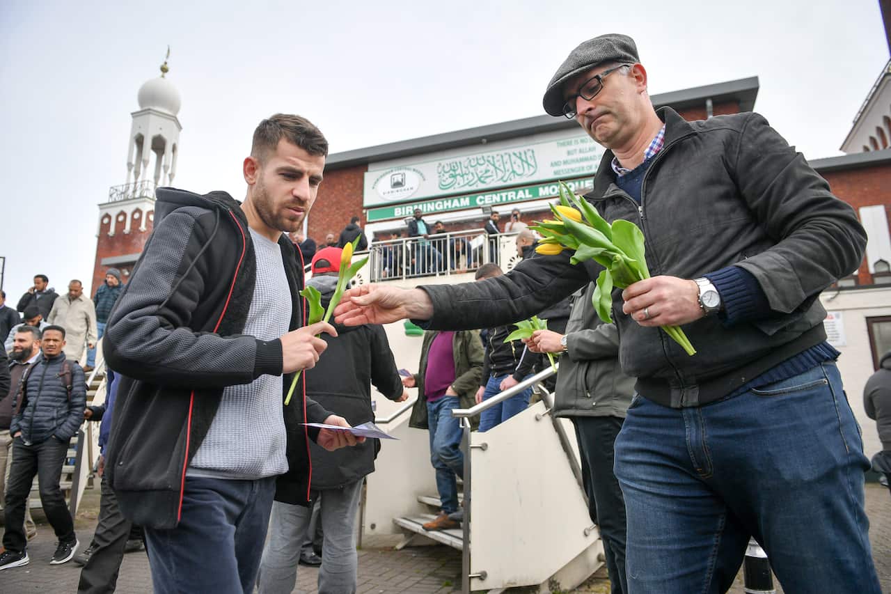 Flowers are handed out at Birmingham Central Mosque as Friday prayers finish after the attack on the Mosque in Christchurch.