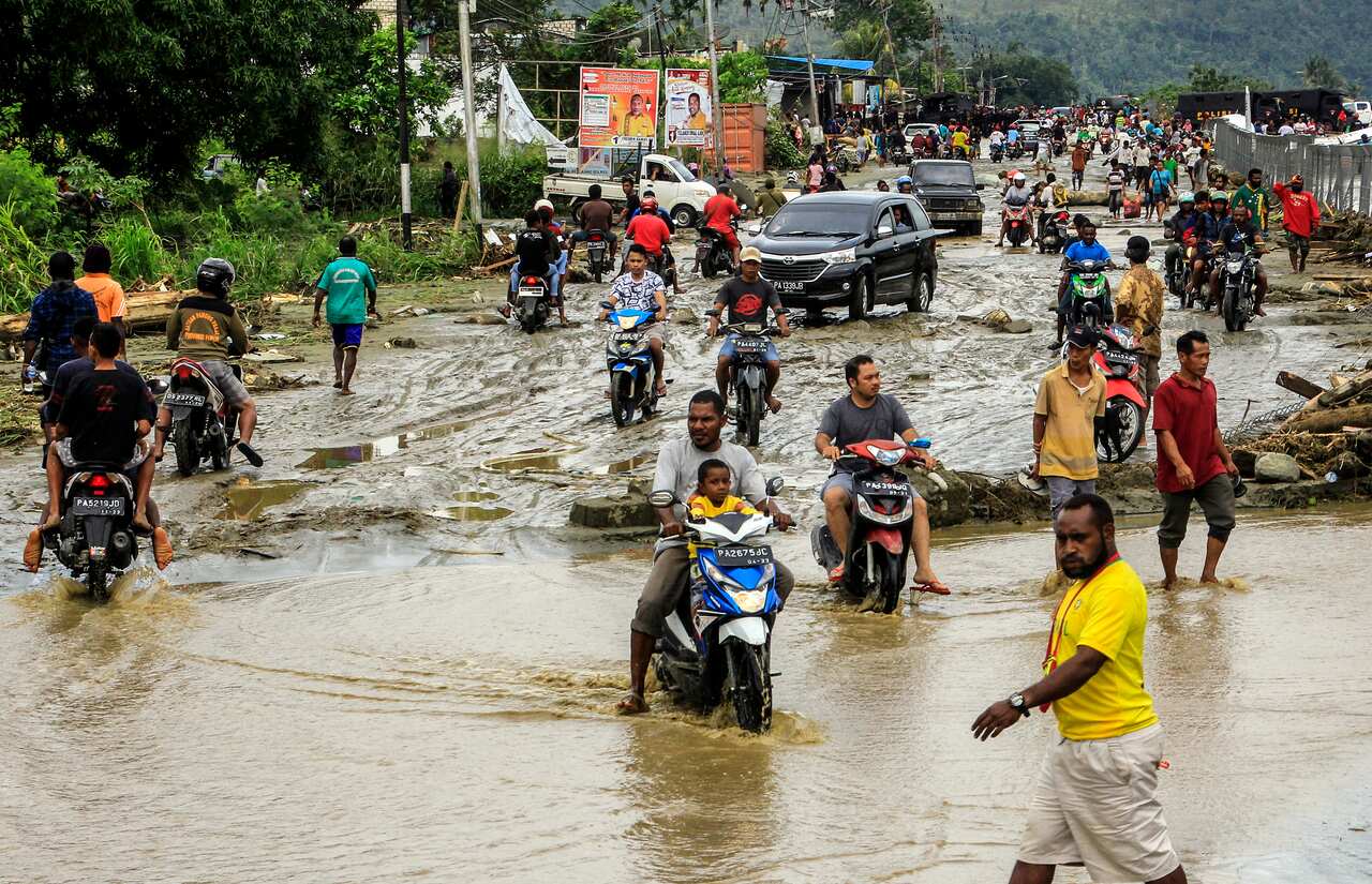 Residents ride through flood water in Sentani, near Jayapura, Papua province, Indonesia.