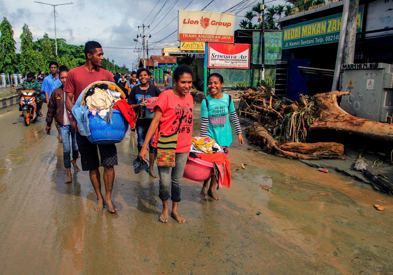 Residents carry their belongings after the flash flood hit the area in Sentani, near Jayapura, Papua province, Indonesia.