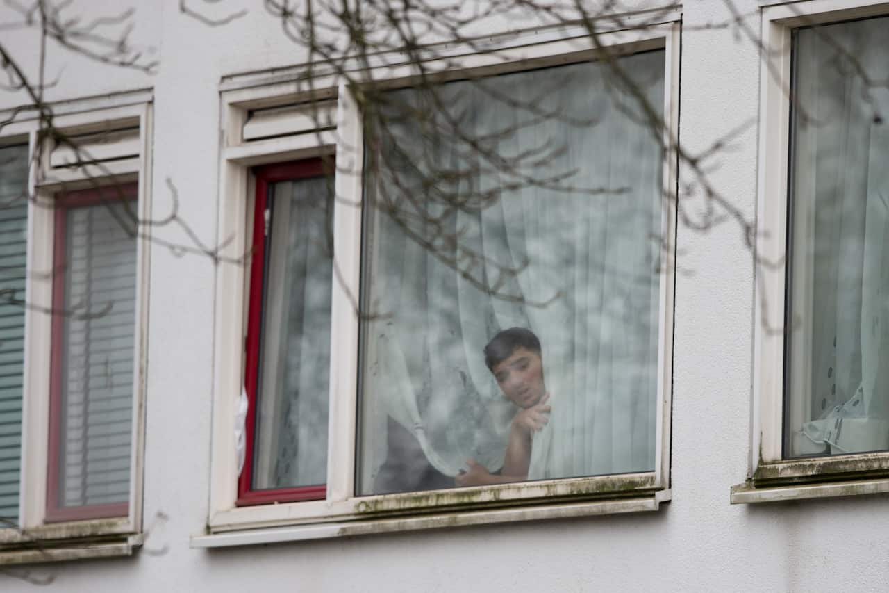 A resident peers out from a window as Dutch counter terrorism police prepare to enter a house after a shooting incident in Utrecht, Netherlands.