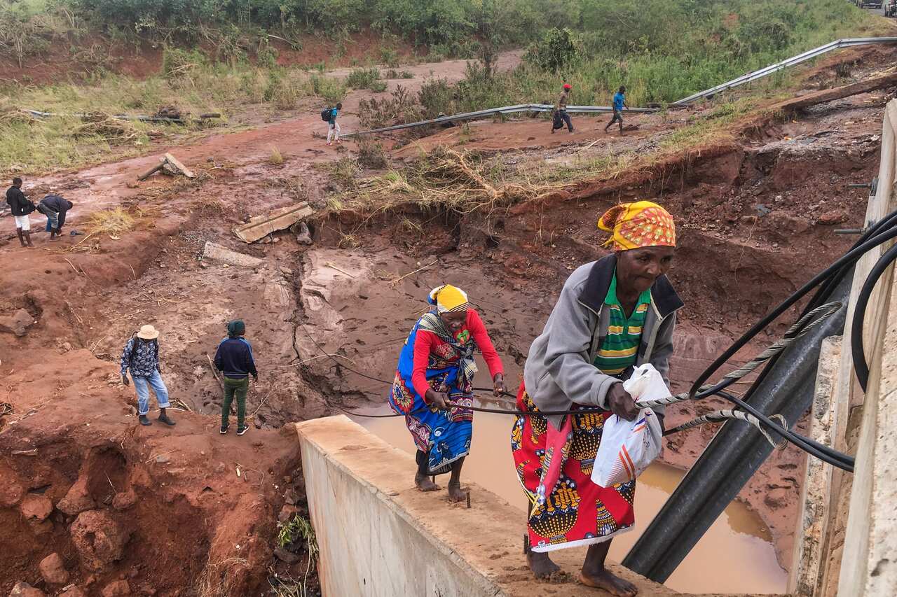 People try to cross the river Munhinga by bypassing a damaged bridge after the passage of the cyclone Idai, Manica province, central Mozambique.