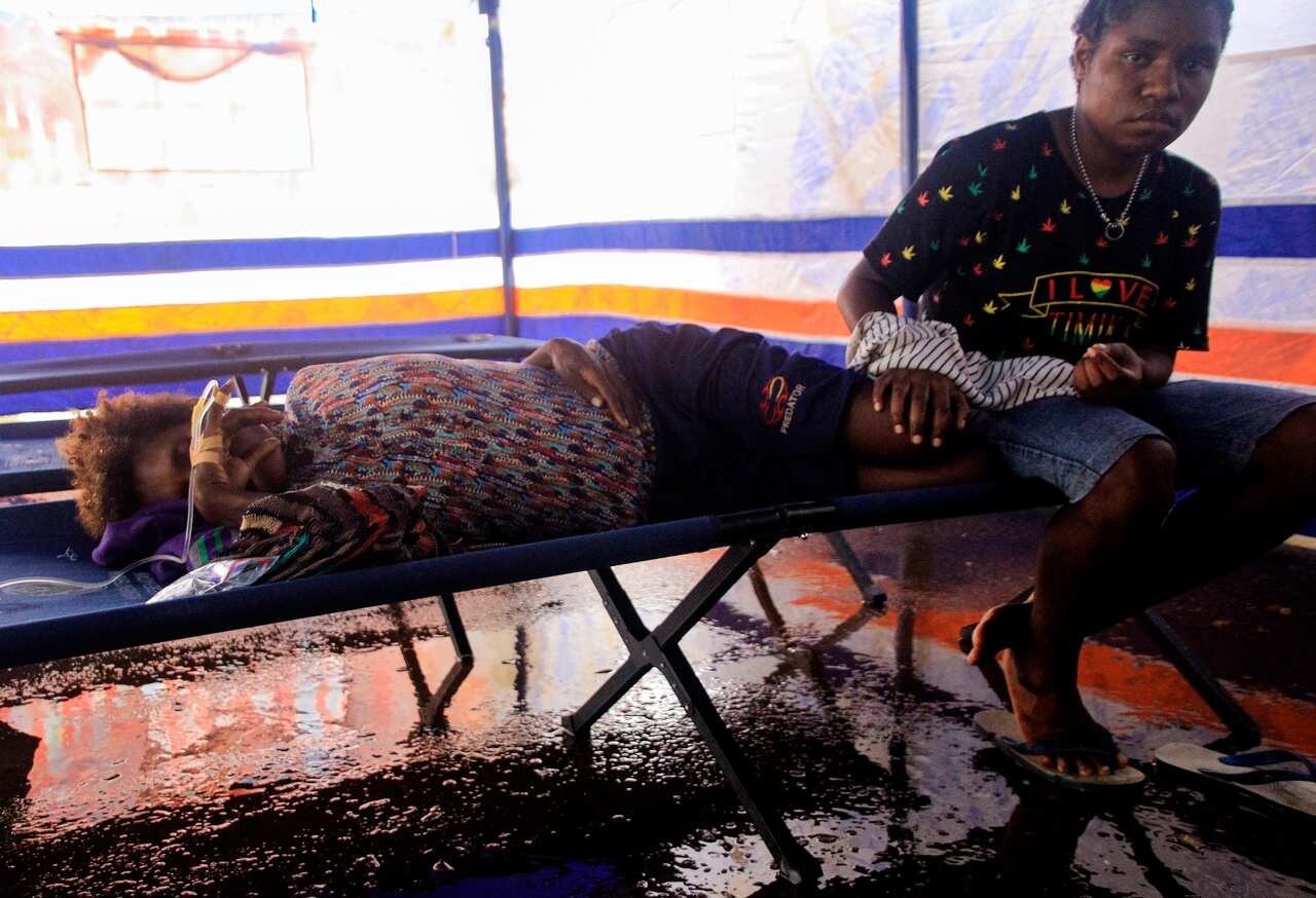 An injured resident lies on the bed as she is accompanied by a relative, at a field hospital in Sentani, near Jayapura, Papua province, Indonesia.