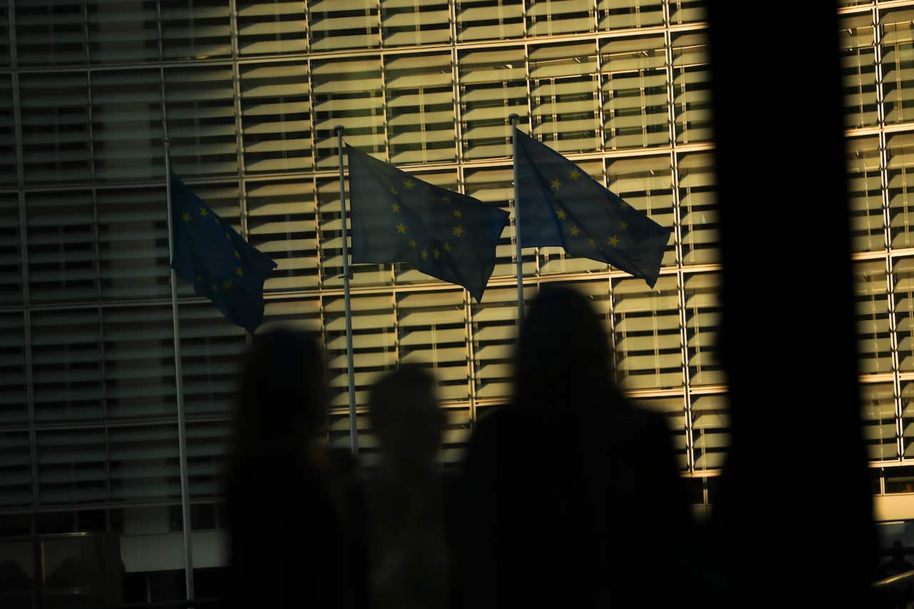 Members of the media look toward EU flags during an EU summit in Brussels.