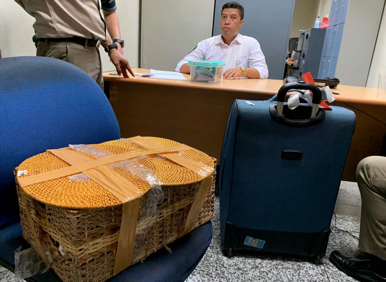 Indonesian officials sit in a room with the belongings of the Russian national